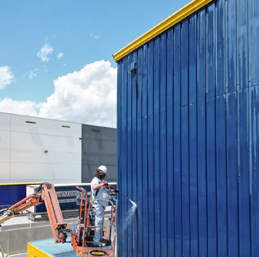 Operario en plataforma elevadora sobre un cerramiento de chapa industrial
